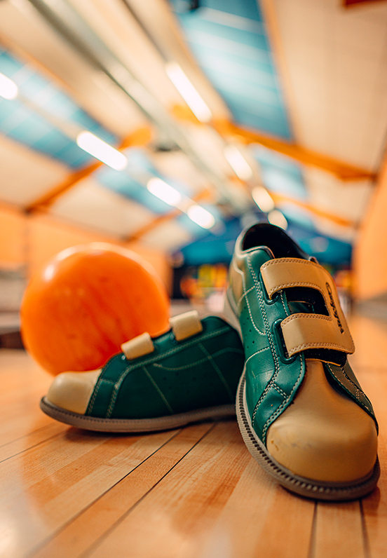 Gros plan sur une boule de bowling et des chaussures posées sur la piste, activité de loisirs proposée par l’association A.R.C.A.D.E.