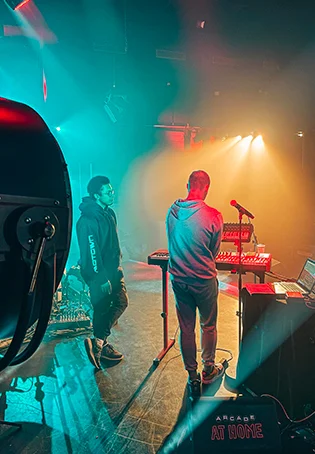 Deux artistes sur la scène de l'A.R.C.A.D.E. en Normandie, illustrant la qualité technique et l'ambiance live d'un concert de musiques actuelles.
