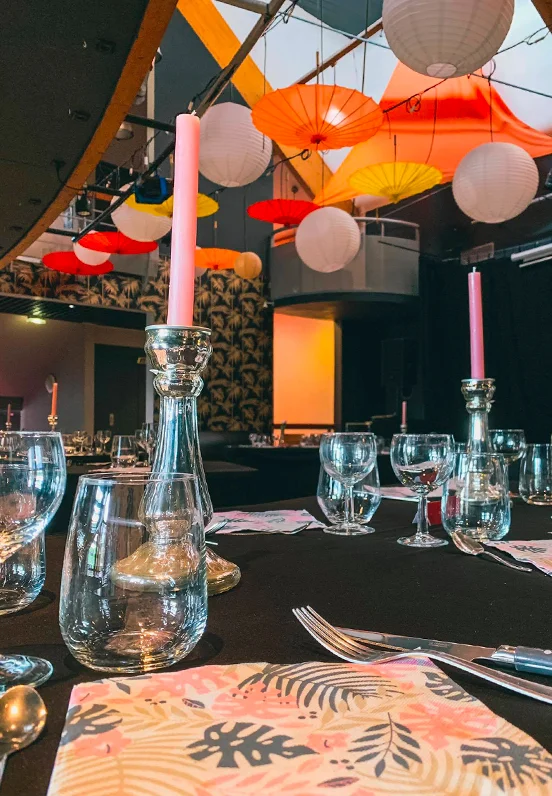 Gros plan sur une table décorée et dressée dans la salle de l'A.R.C.A.D.E., prête à accueillir les convives pour une soirée à thème culturelle et gastronomique.