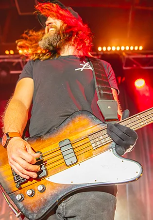 Photo en contre-plongée du bassiste Mandris (Shaka Ponk) en plein concert à l'A.R.C.A.D.E., illustrant l'énergie rock et la notoriété de la salle en Normandie.